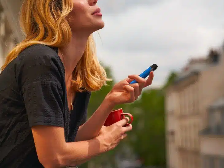 a woman holding a cup and a cell phone