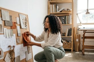 Femme créative aménageant un tableau d'inspiration avec des échantillons de matériaux dans un studio de design d'intérieur