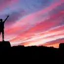 silhouette of man standing on high ground under red and blue skies