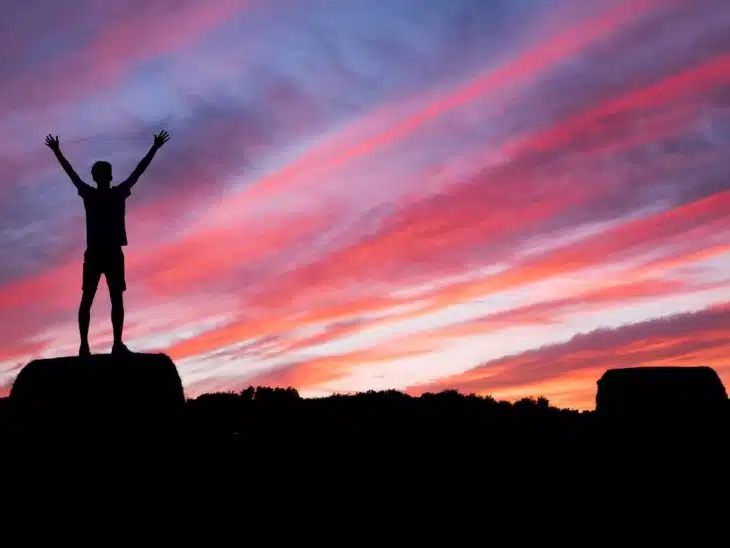 silhouette of man standing on high ground under red and blue skies