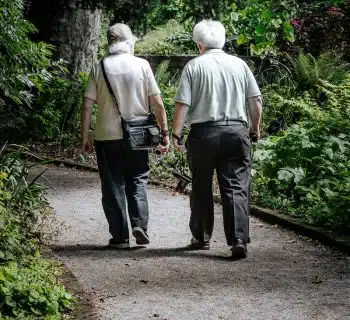 man in white shirt and blue denim jeans walking on pathway