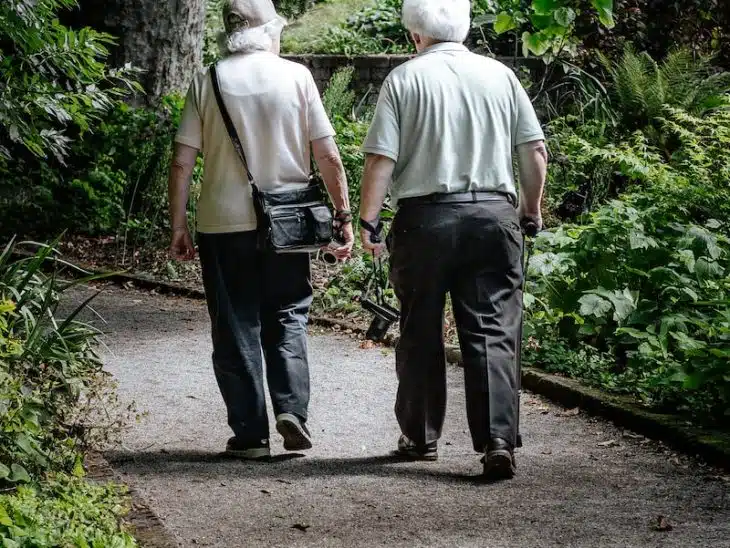 man in white shirt and blue denim jeans walking on pathway