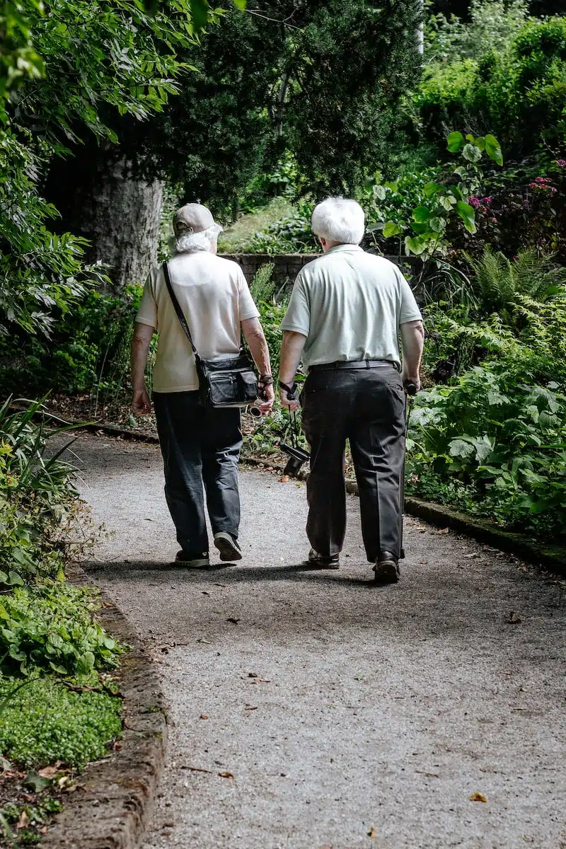 man in white shirt and blue denim jeans walking on pathway